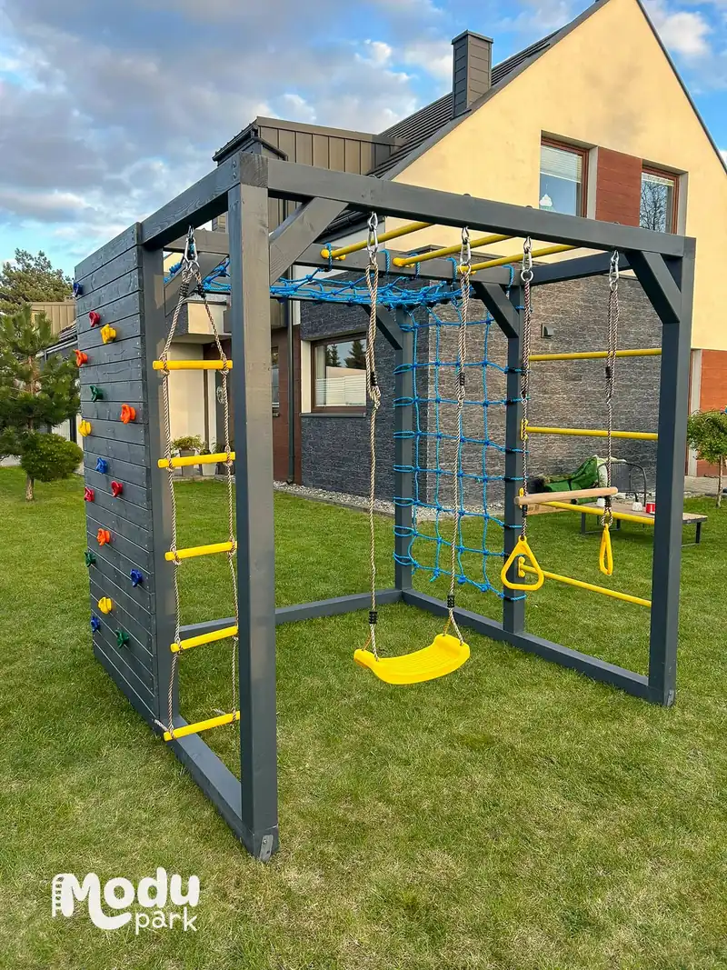 Kompaktowy plac zabaw Gucio ModuPark ustawiony na trawie w niewielkim przydomowym ogrodzie