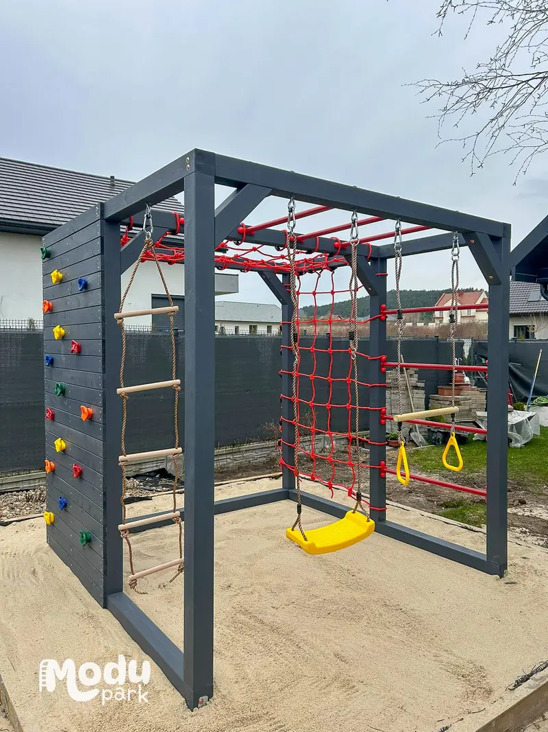 Ściana wspinaczkowa z kolorowymi chwytami, siatka i huśtawka w drewnianym placu zabaw Gucio ModuPark